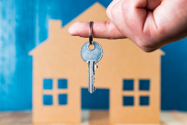 Chiave della porta della mano con la forma della casa su sfondo di legno blu
. - Foto, immagini
