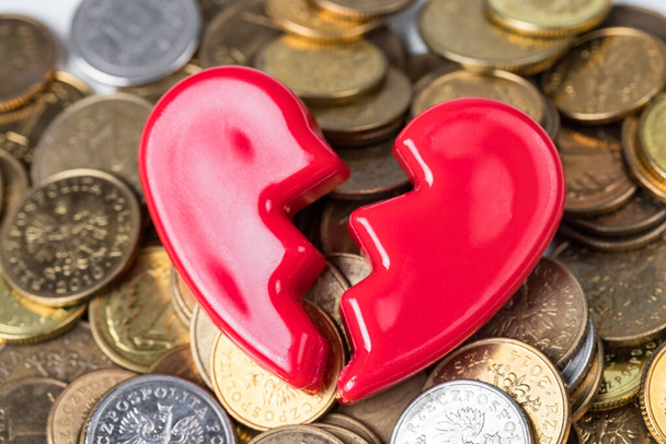 Σπασμένη κόκκινη καρδιά του Αγίου Βαλεντίνου σε ένα σωρό νομίσματα. Αγάπη και χρήμα προβλήματα αφηρημένη έννοια.  - Φωτογραφία, εικόνα