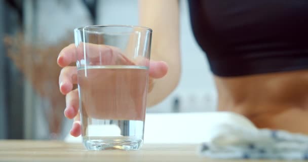 Close up of female hands taking a glass of water from a table in the kitchen. - Imágenes, Vídeo
