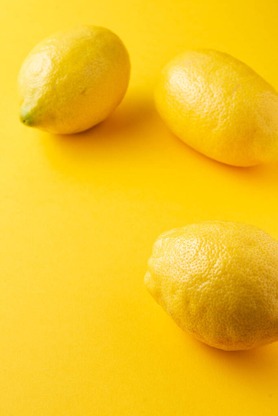 Top view of three lemons on yellow background, selective focus, vertical, with copy space - Foto, Bild