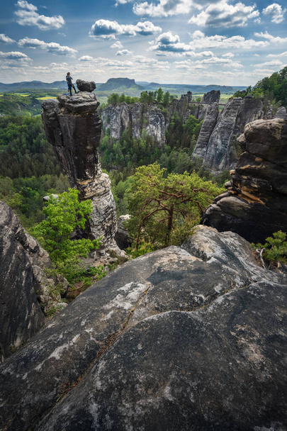 Unrecognized silhouette climber on mountain top enjoying famous Bastei rock formation of national park Saxon Switzerland, Germany. Spring season active travel adventure - Foto, afbeelding