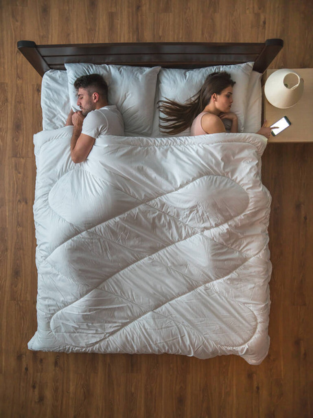 A nő riadót fújt az ágyra a férj mellett. felülnézetből - Fotó, kép