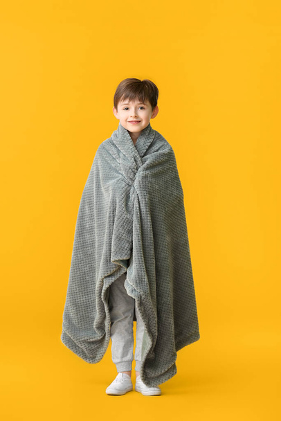 Little boy wrapped in plaid on color background - Photo, Image