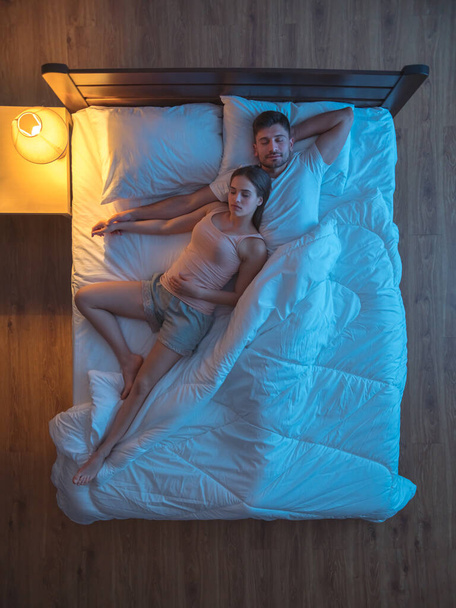 Το ευτυχισμένο ζευγάρι που κοιμάται στο κρεβάτι. Βράδυ βράδυ. θέα από ψηλά - Φωτογραφία, εικόνα