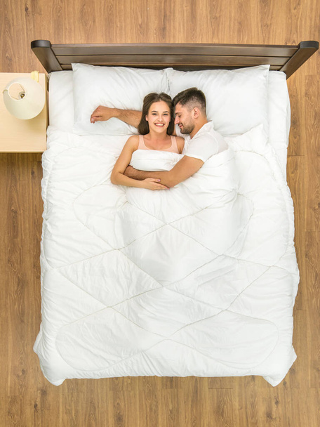 The happy couple sleeping on the bed. View from above - Фото, изображение