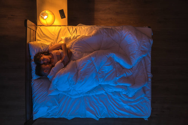 The couple sleeping on the bed. Evening night time. View from above - Photo, Image