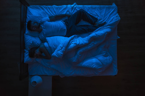 The man and woman sleeping on a bed. Evening night time. View from above - Foto, imagen