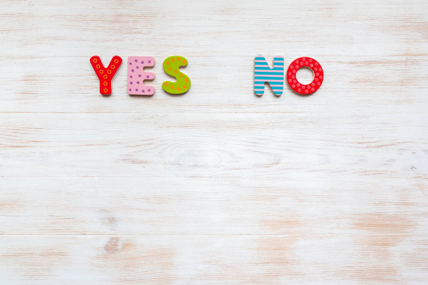 Words YES and NO of colorful letters on vintage wood background. Colored words YES and NO on wood background with copy space. Choosing right answer concept. - Photo, image