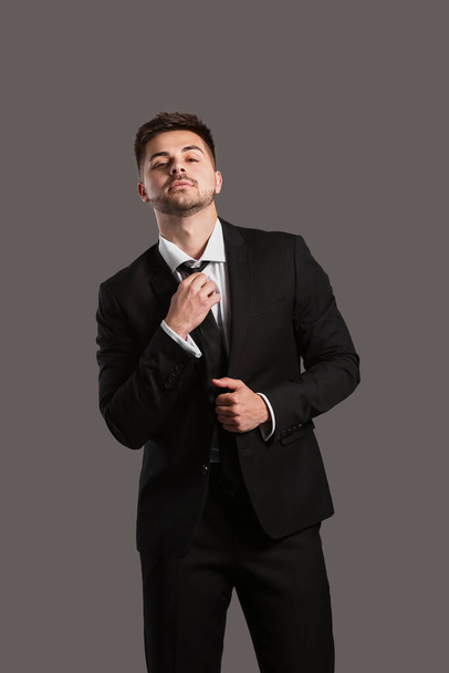 Handsome young man in elegant suit on grey background - 写真・画像