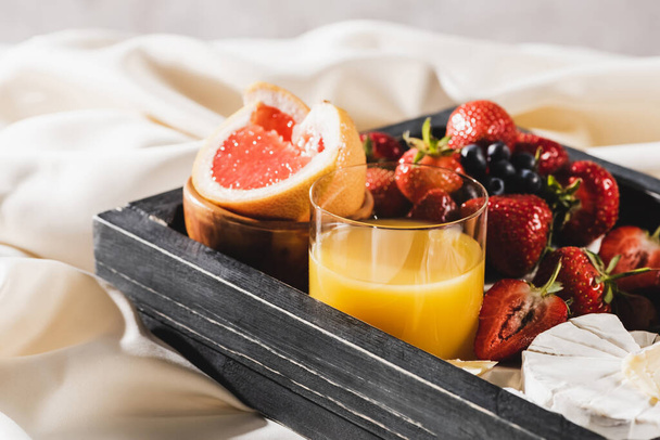 close up view of french breakfast with grapefruit, Camembert, orange juice, berries on wooden tray - Photo, Image