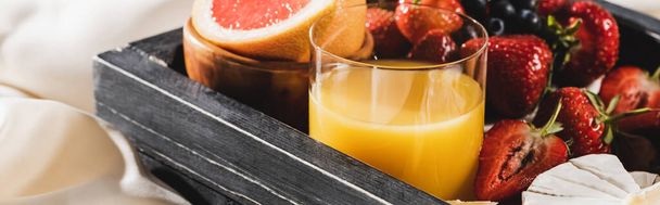 widok z bliska na francuskie śniadanie z grejpfrutem, Camembert, sok pomarańczowy, jagody na drewnianej tacy, panoramiczne ujęcie - Zdjęcie, obraz