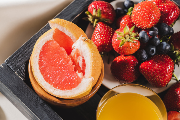 закрытый вид на французский завтрак с грейпфрутом, апельсиновым соком, ягодами на деревянном трамвае
 - Фото, изображение