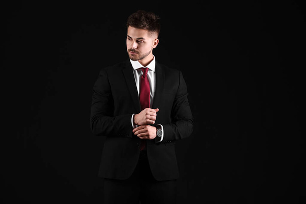 Handsome young man in elegant suit on dark background - 写真・画像