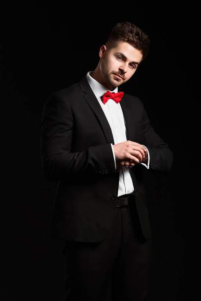 Knappe jongeman in elegant pak op donkere achtergrond - Foto, afbeelding