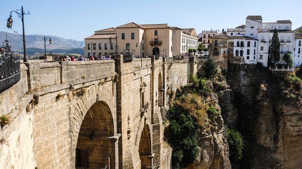 Puente Nuevo famous new bridge in the heart of old village Ronda in Andalusia, Spain. Touristic landmark on a sunny day with buildings in the background. Side angle view. - Photo, Image