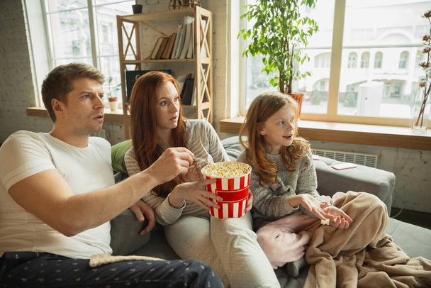 Familie verbringt schöne Zeit zu Hause, sieht glücklich und fröhlich aus, schaut fern - Foto, Bild