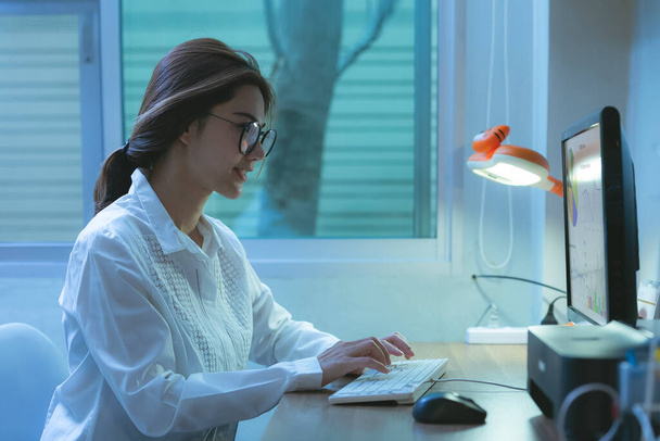 Joven asiática hembra en gafas usando ordenador, se comunica en internet con el cliente en casa. Concepto de aprendizaje E
 - Foto, Imagen