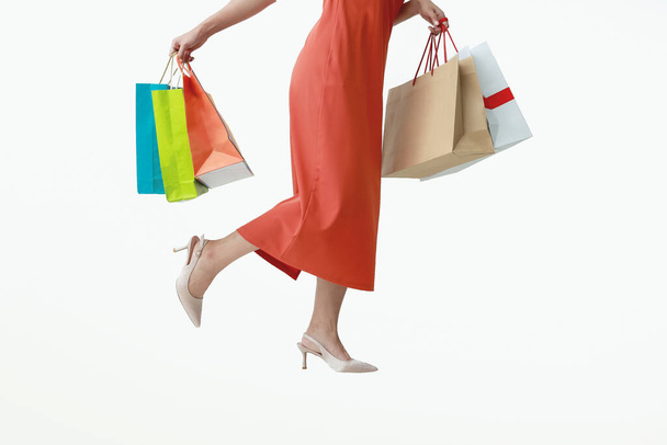 Woman of half body in red pants holding multicolored shopping bags isolated white background. - Photo, Image