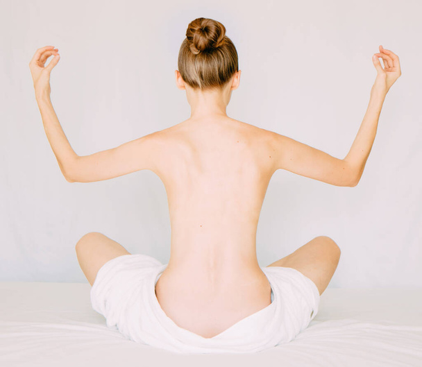 Junge schöne nackte Frau mit Handtuch praktiziert Yoga, isoliert auf weiß - Foto, Bild