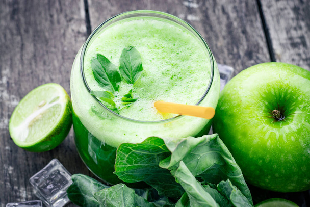 Zelený jablečný koktejl ve skle a kapustové listy na venkovském dřevěném stole. Letní detox shake pozadí - Fotografie, Obrázek