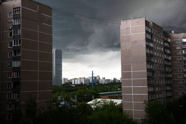 donderwolken klampen zich vast aan hoge flatgebouwen - Foto, afbeelding