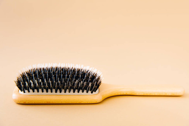 Wooden comb for hair with natural material, lies on beige background. Hair care concept. - Photo, Image