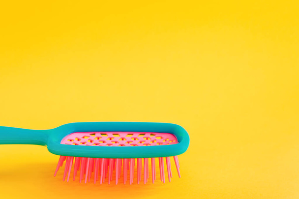 Leuchtend gefärbte Haarbürste in Nahaufnahme auf gelbem Hintergrund. Haarpflegekonzept. Schönheit und Stil. - Foto, Bild