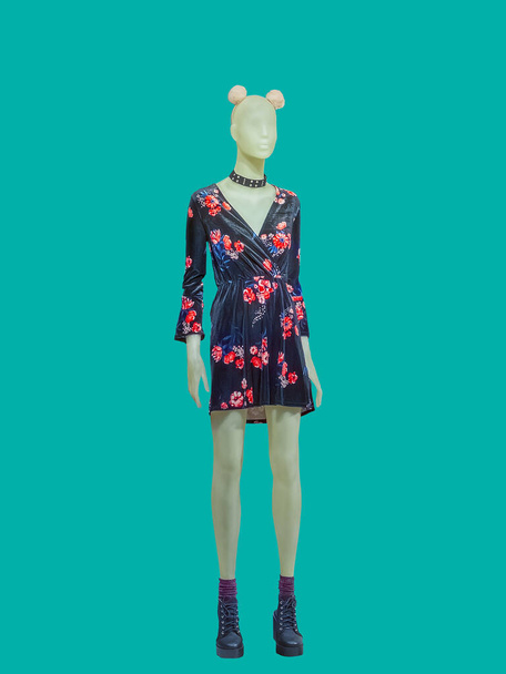 Ganzkörperlange weibliche Schaufensterpuppe trägt ein modisches Kleid mit Blumenmuster, isoliert auf grünem Hintergrund. Keine Markennamen oder Copyrightobjekte. - Foto, Bild