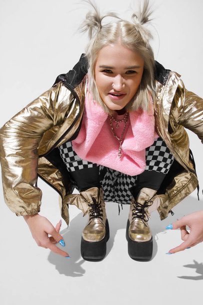 bela menina da moda posando em estúdio vestido com uma jaqueta brilhante e calças xadrez
 - Foto, Imagem