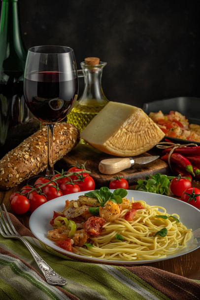 Spaghetti with shrimps, cherry tomatoes and spices on wooden background.  Food background. - 写真・画像