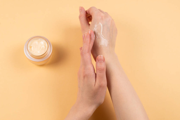 Crème pour les mains et les mains de femme sur un fond beige. Espace de copie
.  - Photo, image