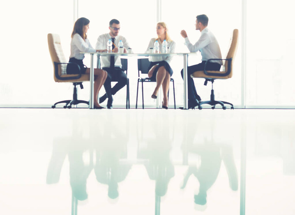 Четверо бизнесменов сидят за столом на конференции
 - Фото, изображение