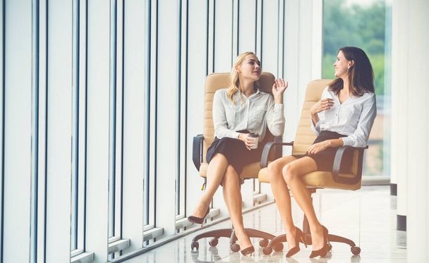 De gelukkige zakenvrouwen op stoelen praten op de achtergrond van de zon - Foto, afbeelding