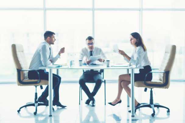 Три бизнесмена сидят за столом для конференций
 - Фото, изображение