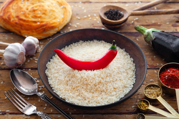 Pilaf ingrediënten, rijst, groenten, pita, bestek, specerijen op rustieke achtergrond - Foto, afbeelding