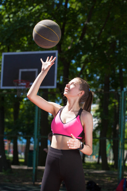 Young beautiful girl with a basketball ball posing on the playground - Φωτογραφία, εικόνα