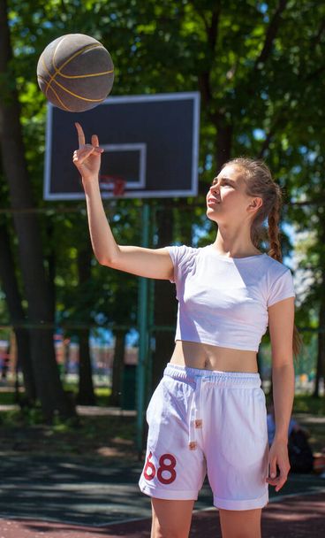 Young beautiful girl with a basketball ball posing on the playground - Fotoğraf, Görsel