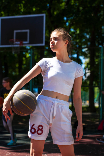 Young beautiful girl with a basketball ball posing on the playground - Fotó, kép