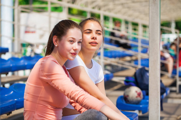 Two young athletes are resting on the podium of the stadium - Photo, Image