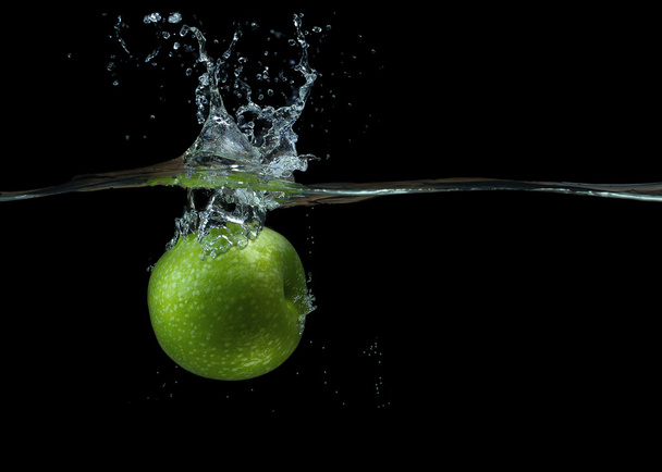 зелене яблуко у воді з бризкою і краплями
 - Фото, зображення