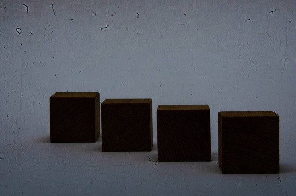 Дерев'яні кубики на білому тлі. Чотири однакових кубики лежать, стояти в ряд разом і окремо, прямо і під кутом. Кубики в темряві
 - Фото, зображення