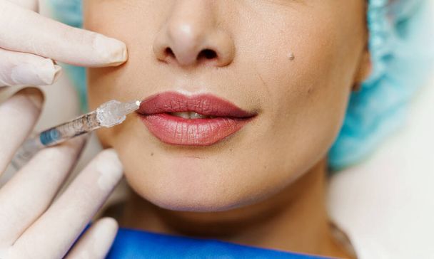 Closeup lábios aumento injeções para menina atraente. O cirurgião plástico faz a injeção no lábio na clínica médica. Tratamento facial rejuvenescedor cosmético. Espaço vazio para o anúncio
 - Foto, Imagem