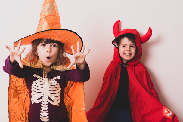 Onnellinen veli ja sisko Halloweenina. Hauskoja lapsia karnevaalipuvuissa sisätiloissa.  - Valokuva, kuva