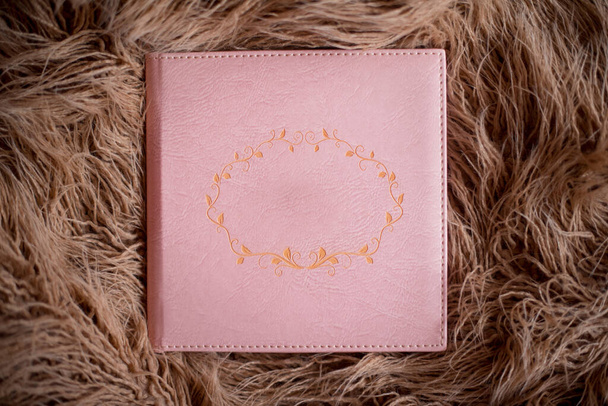 Růžový fotobook v koženém obalu leží na hnědé kožešině. Volné místo pro titul. Horní pohled - Fotografie, Obrázek