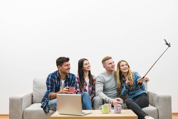 The four people make a selfie on the sofa on the white wall background - Fotoğraf, Görsel