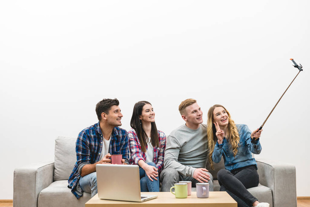 The four friends make a selfie on the sofa on the white wall background - Photo, image