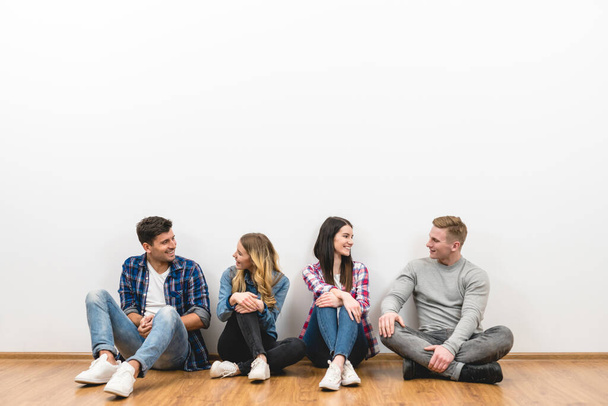 Czterech szczęśliwych przyjaciół siedzi na podłodze na białym tle - Zdjęcie, obraz