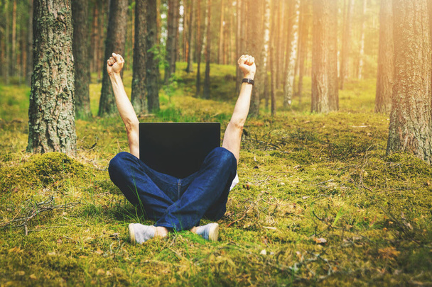 telecomutação - homem com laptop que coloca no musgo na floresta com as mãos levantadas
 - Foto, Imagem