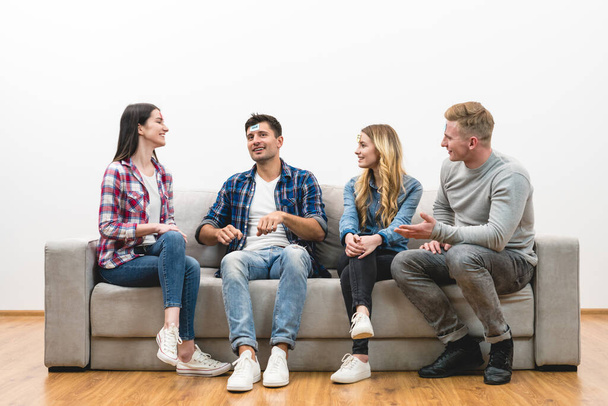 Четверо счастливых друзей на диване играют в игру на белом фоне стены
 - Фото, изображение