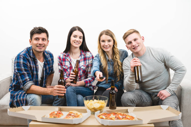 Les quatre heureux regardent la télévision avec une pizza et une bière sur le fond blanc
 - Photo, image